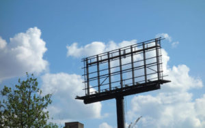 Empty billboard against a blue sky with clouds