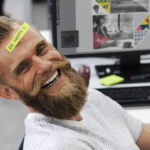 Happy, smiling man with a beard and a sticker on his head that says "Be happy"