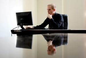 Man using an application on his computer, his hand on his chin in thought