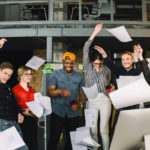 Photo of a group of marketing and salespeople throwing papers up into the air