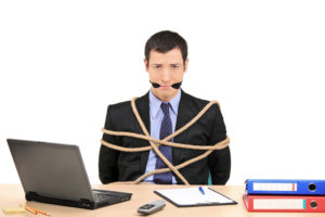Photo of a man tied up and gagged behind a desk to symbolize a website developer holding him hostage