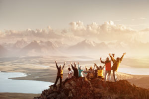 happy people climbing mountain in the sunset
