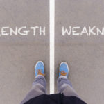 Strength and weakness text on asphalt ground, feet and shoes on